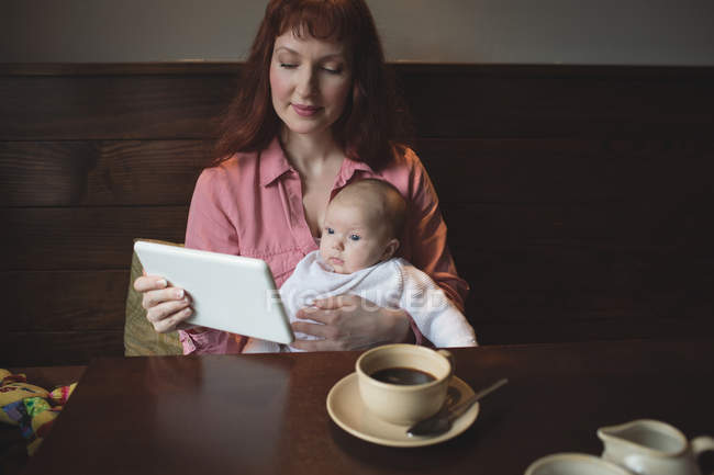 Mère avec bébé fille en utilisant une tablette numérique dans le café — Photo de stock