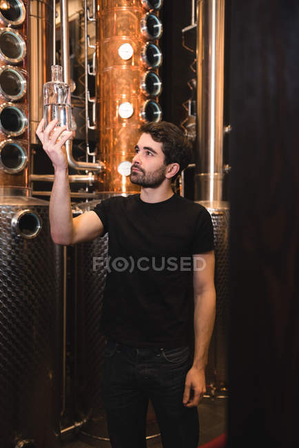 Человек осматривает бутылку алкоголя на пивной фабрике — стоковое фото