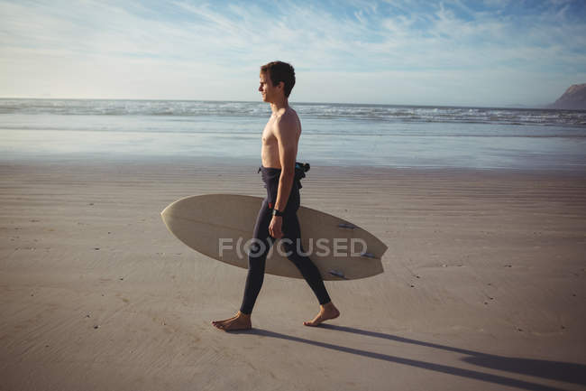 Серфер, що йде з дошкою для серфінгу на пляжі — стокове фото