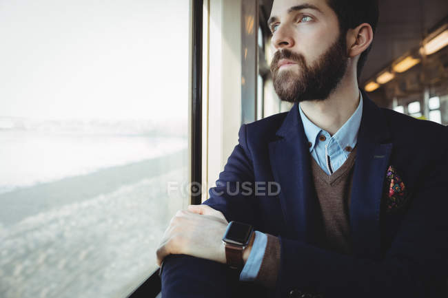 Nachdenklicher Geschäftsmann blickt durch Zugfenster — Stockfoto