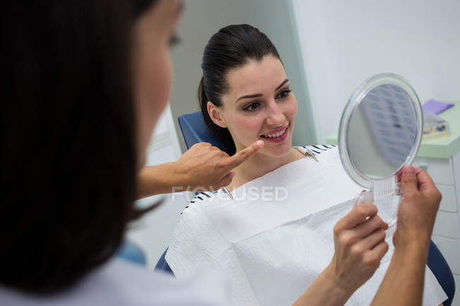 Dentiste montrant miroir à la patiente à la clinique — Photo de stock