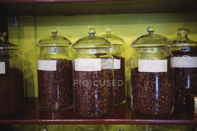 Primer plano de frascos de granos de café dispuestos en el estante en la tienda - foto de stock