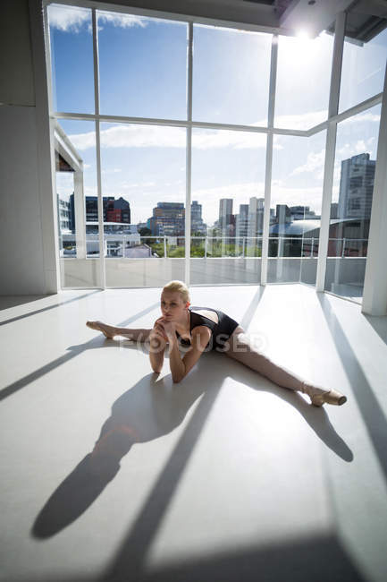 Bailarina esticando-se no chão no estúdio — Fotografia de Stock