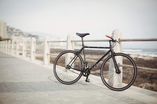 Bicycle leaning by promenade railing near the sea shore — Stock Photo