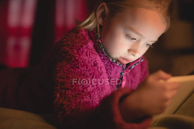 Девочка младшего возраста использует цифровой планшет в спальне дома, крупным планом — стоковое фото