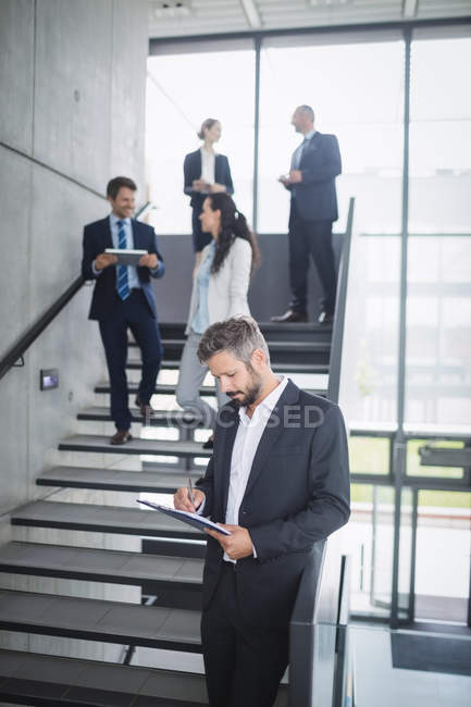 Бизнесмен пишет на буфере обмена в офисе — стоковое фото