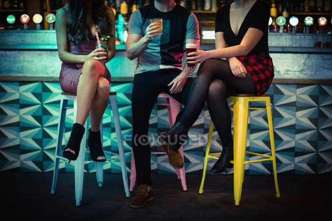 Amis dégustant des boissons alcoolisées au comptoir du bar — Photo de stock