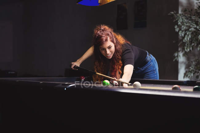 Beautiful woman playing pool playing pool in the billiards club — Stock Photo