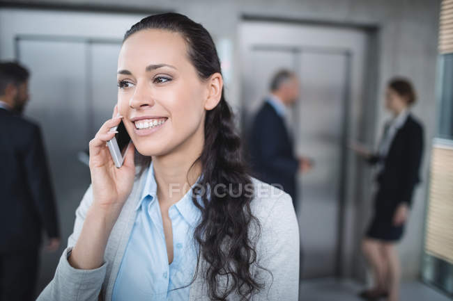Деловая женщина разговаривает по мобильному телефону в офисе — стоковое фото