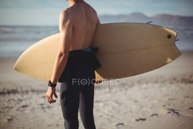 Середній розділ серфінгу, що стоїть з дошкою для серфінгу на пляжі — стокове фото