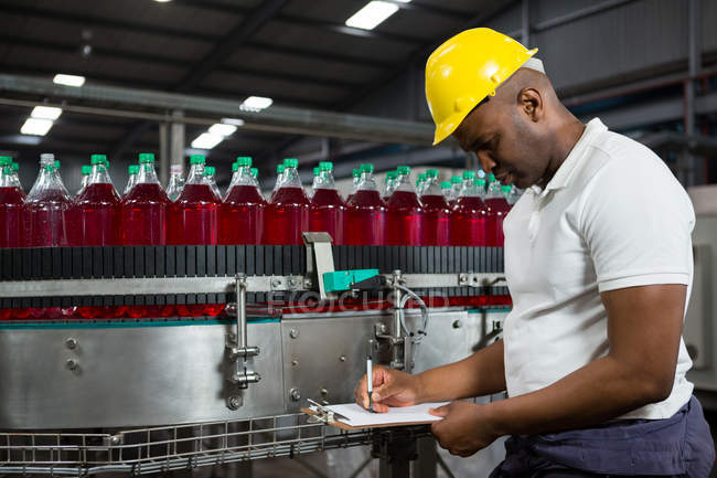 Young male worker noting about products in factory — Stock Photo