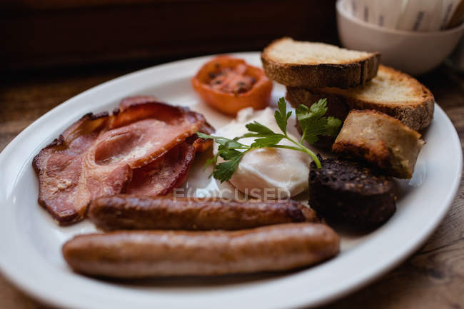 Primer plano del desayuno inglés con pudín negro en el plato en la mesa - foto de stock