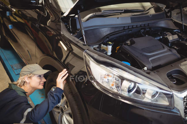 Meccanico donna esaminando una ruota di auto in garage di riparazione — Foto stock
