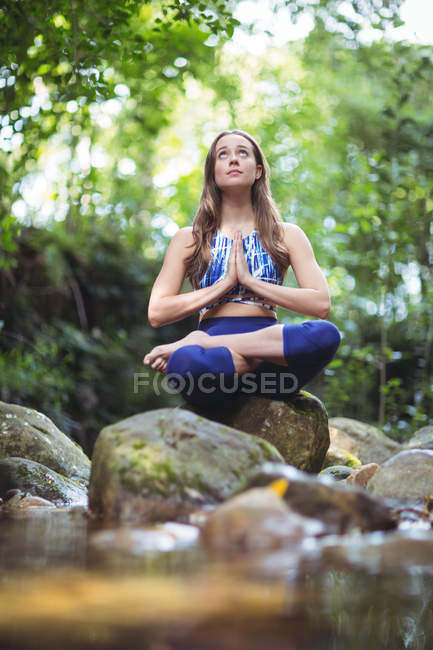 Mujer meditando en posición de loto en el bosque - foto de stock