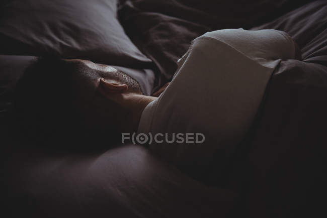 Вид сзади на человека, спящего в своей постели в спальне дома — стоковое фото