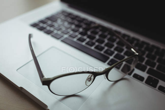Крупним планом окуляри на ноутбуці в офісі — стокове фото