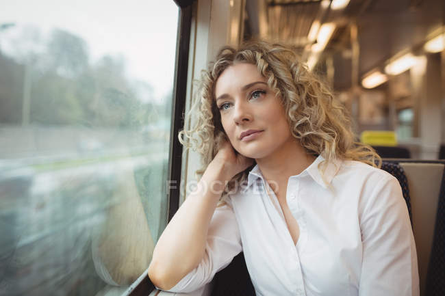 Thoughtful businesswoman looking through window while travelling — Stock Photo