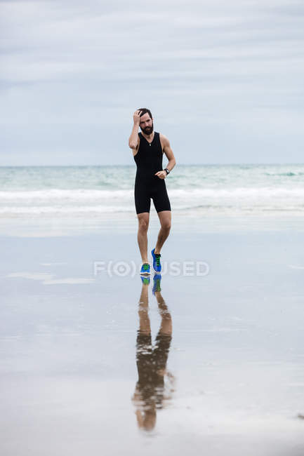 Beau athlète jogging sur la plage — Photo de stock