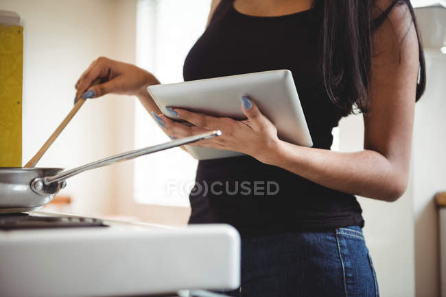 Середина жінки, що готує і використовує цифровий планшет на кухні — стокове фото