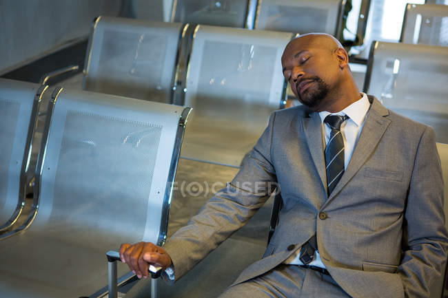 Empresario durmiendo en la zona de espera en la terminal del aeropuerto - foto de stock