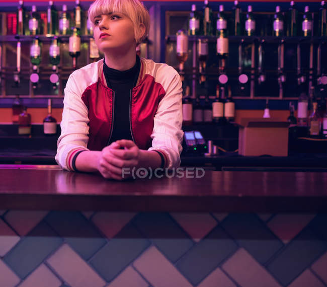 Задумчивая барменша, стоящая у барной стойки — стоковое фото