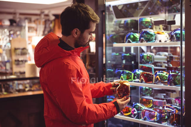 Мужчина выбирает лыжные очки в магазине — стоковое фото