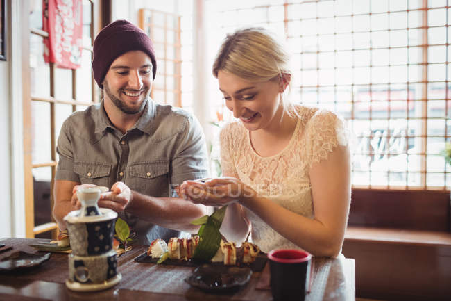 Casal tendo sake enquanto come sushi no restaurante — Fotografia de Stock