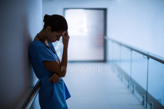 Enfermera triste parada en el pasillo en el hospital - foto de stock