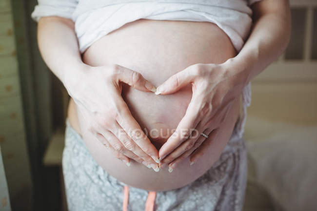 Parte média da mulher grávida tocando sua barriga no quarto em casa — Fotografia de Stock