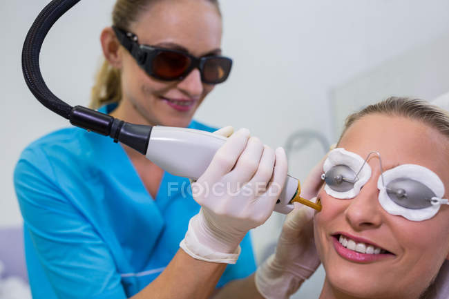 Mujer recibiendo tratamiento de depilación láser en la cara en el salón de belleza - foto de stock