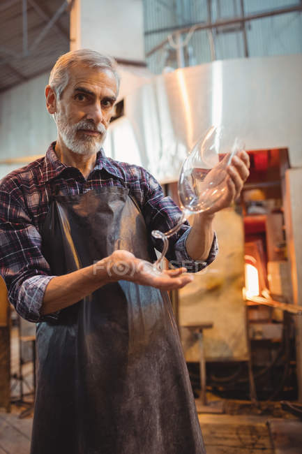 Retrato del soplador de vidrio que sostiene una cristalería en la fábrica de soplado de vidrio - foto de stock