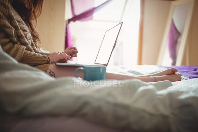 Frau benutzt Laptop auf dem Bett zu Hause — Stockfoto