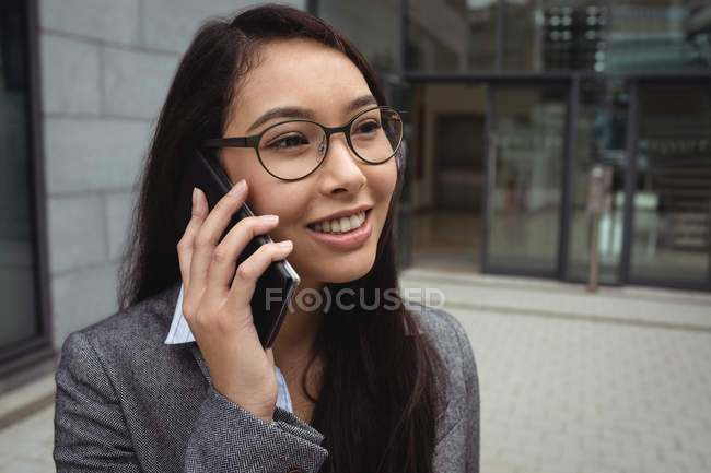 Femme d'affaires parlant sur téléphone portable à l'extérieur de l'immeuble de bureaux — Photo de stock