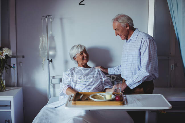 Senior woman interacting with senior man in the ward at hospital — Stock Photo