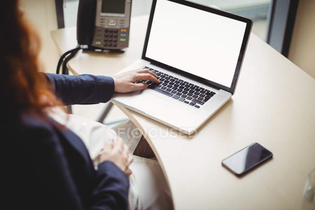 Cropped view of pregnant businesswoman using laptop in office — Stock Photo