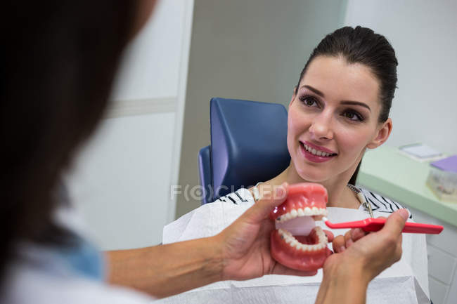 Dentist showing set of model teeth to patient in clinic — Stock Photo