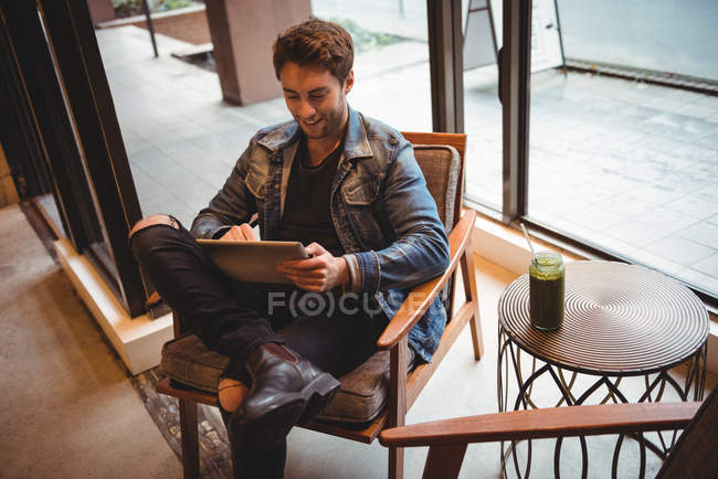 Чоловік сидить на стільці і використовує цифровий планшет у кафе — стокове фото
