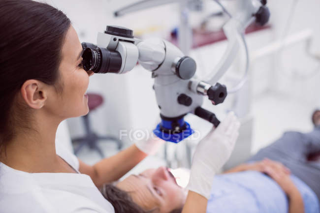 Dentista feminina examinando paciente na clínica — Fotografia de Stock