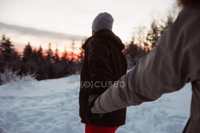 Casal de pé e segurando a mão na montanha coberta de neve — Fotografia de Stock