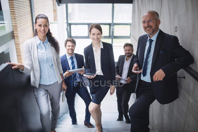 Porträt selbstbewusster Geschäftsleute, die im Büro auf der Treppe stehen — Stockfoto