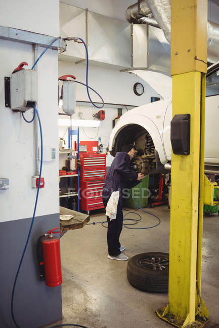 Mecânico examinando um freio de disco de roda de carro na garagem de reparo — Fotografia de Stock
