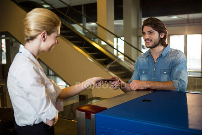 Female staff giving the boarding pass to the passenger in the airport terminal — Stock Photo