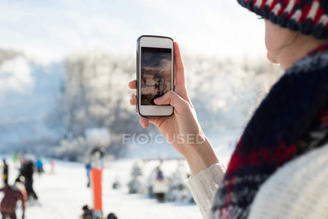 Nahaufnahme einer Frau, die Skifahrer im Skigebiet fotografiert — Stockfoto