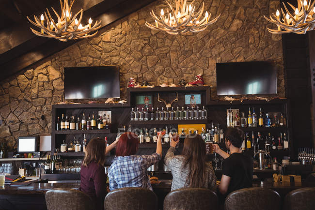 Rückansicht von Freunden beim Anstoßen mit Bier und Cocktailgläsern in der Bar — Stockfoto