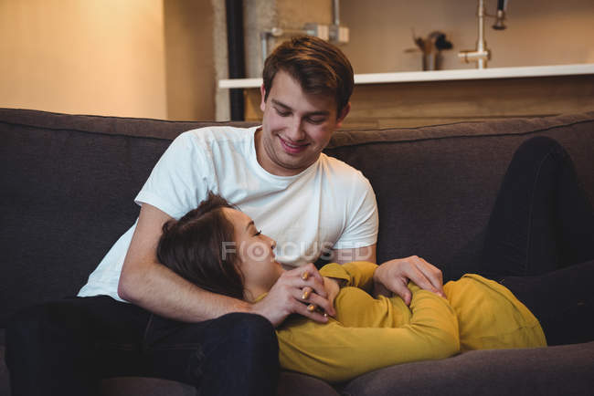 Веселая пара, лежащая вместе на диване в гостиной дома — стоковое фото