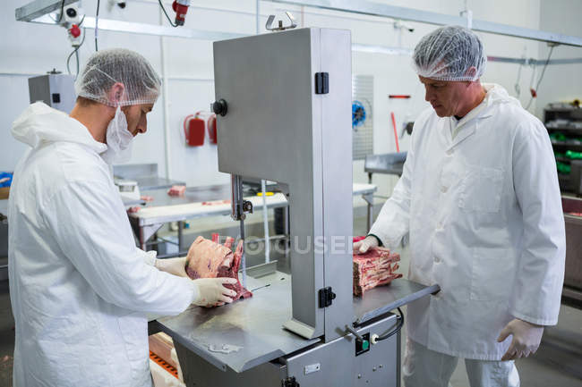 Metzger schneiden rohes Fleisch an Bandsägemaschine in Fleischfabrik — Stockfoto