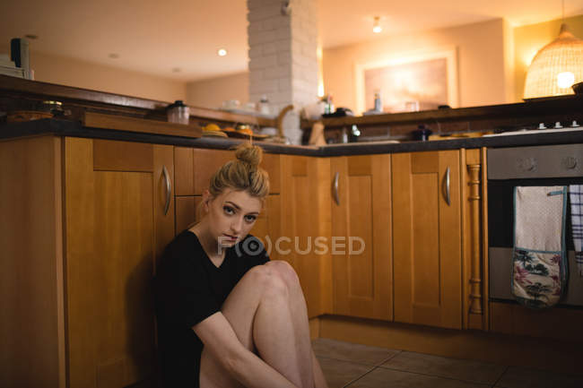 Mulher pensativa sentada na cozinha em casa — Fotografia de Stock