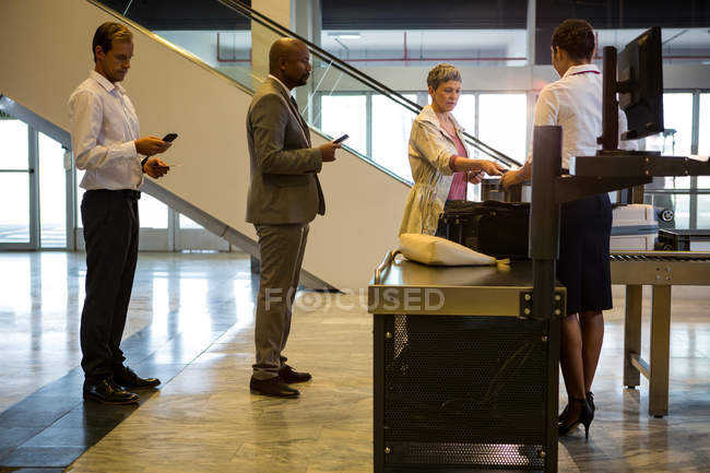 Airline check-in attendant handing boarding pass to passengers at airport check-in counter — Stock Photo