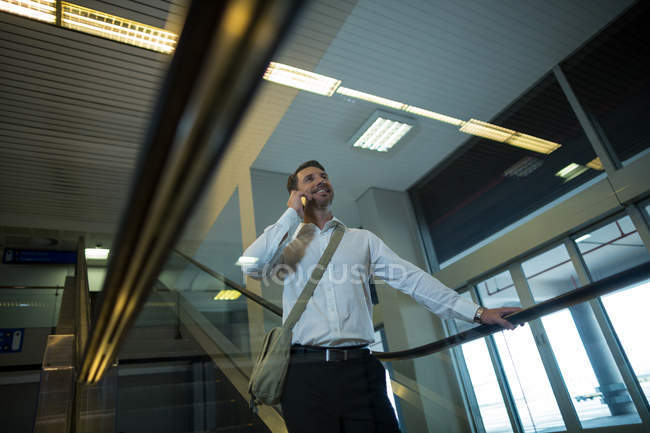 Schöner Mann telefoniert auf Rolltreppe im Flughafen — Stockfoto