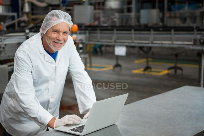Retrato de trabalhador masculino feliz usando laptop na fábrica — Fotografia de Stock
